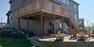 large patio space with deck above and stairs coming down